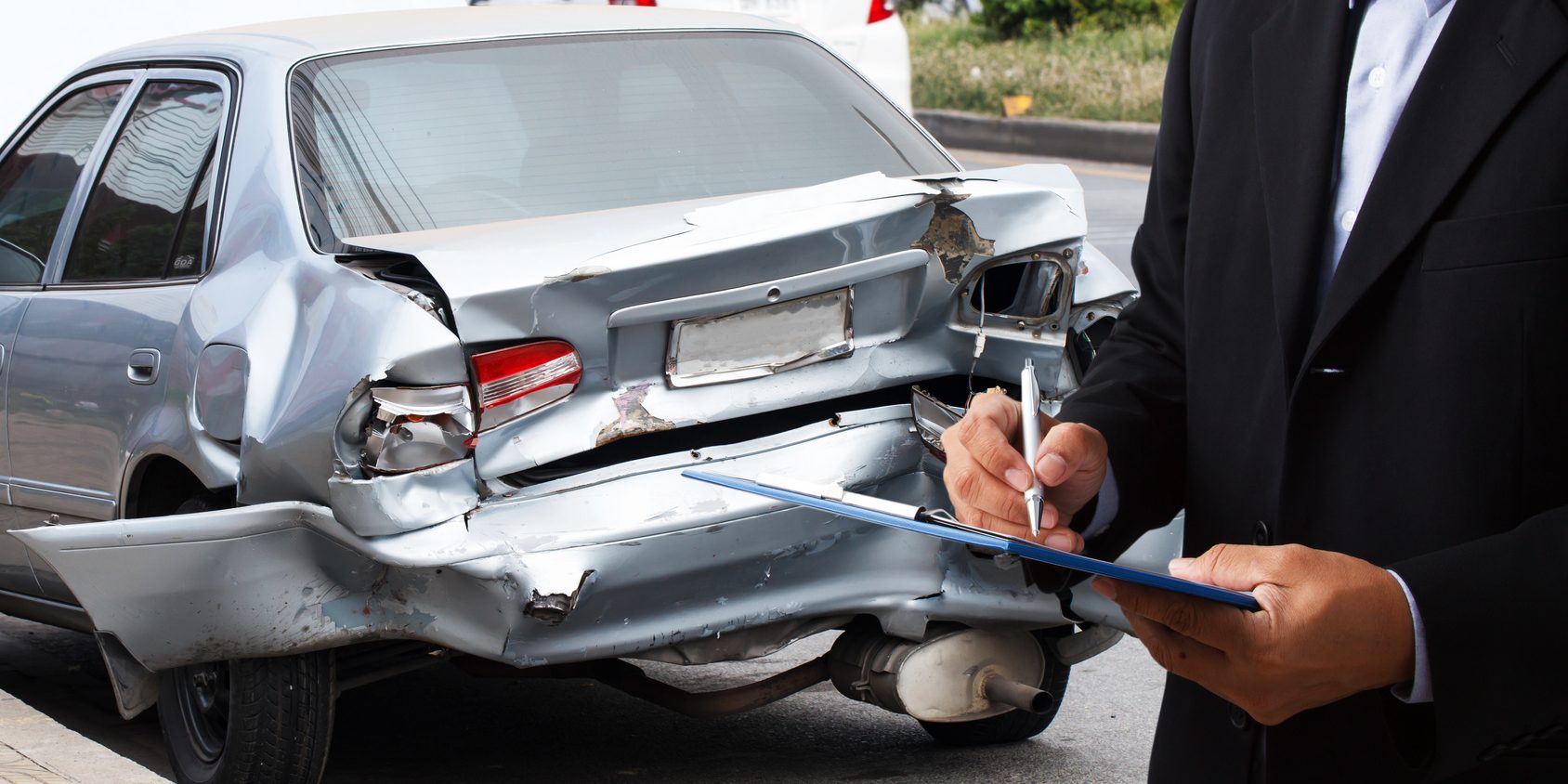 Car insurance agents writing clipboard of car accident-damaged as a proof of insurance claim